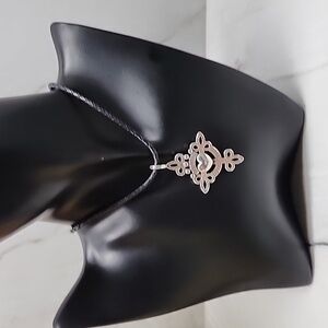 Brighton cross necklace on leather cord. Plated silver